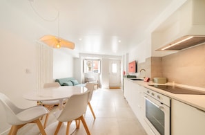 Een moderne keuken met witte kasten, een ingebouwde oven en een eethoek met een ronde tafel en stoelen.