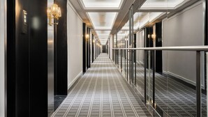 A hotel corridor with a checkered floor, wall-mounted light fixtures, and a glass railing. - XANA Deluxe International Hotel Guangzhou East Railway Station Branch - Free Shuttle Bus to Canton Fair Complex During Canton Fair Period (Guangzhou)