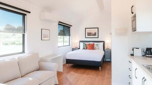 Un dormitorio moderno con cama, mesitas de noche, un sofá y una kitchenette.