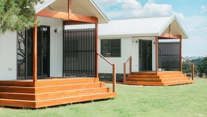 Dos cabañas modernas con terrazas de madera y techos de metal.