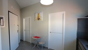 Käytävä, jossa on kaksi ovea, ruokapöytä tuoleineen ja seinällä oleva taulu.