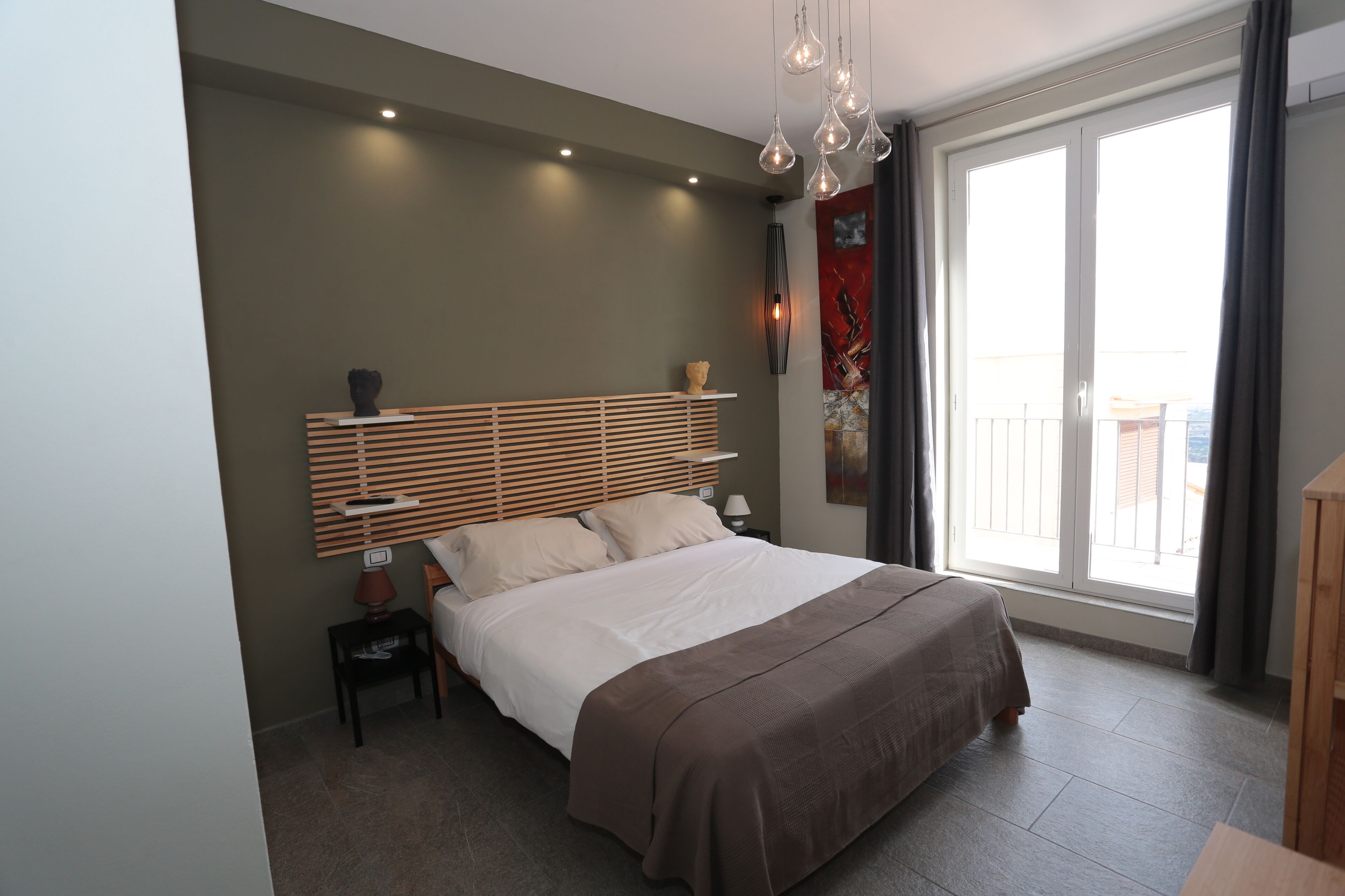 Ein modernes Schlafzimmer mit einem großen Bett, einem Nachttisch und einem Fenster mit Vorhängen.