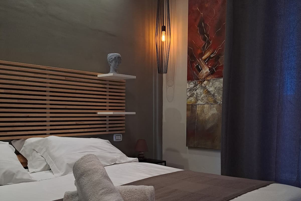 A neatly made bed with white linens, a wooden headboard, and a brown bedside table with a lamp.