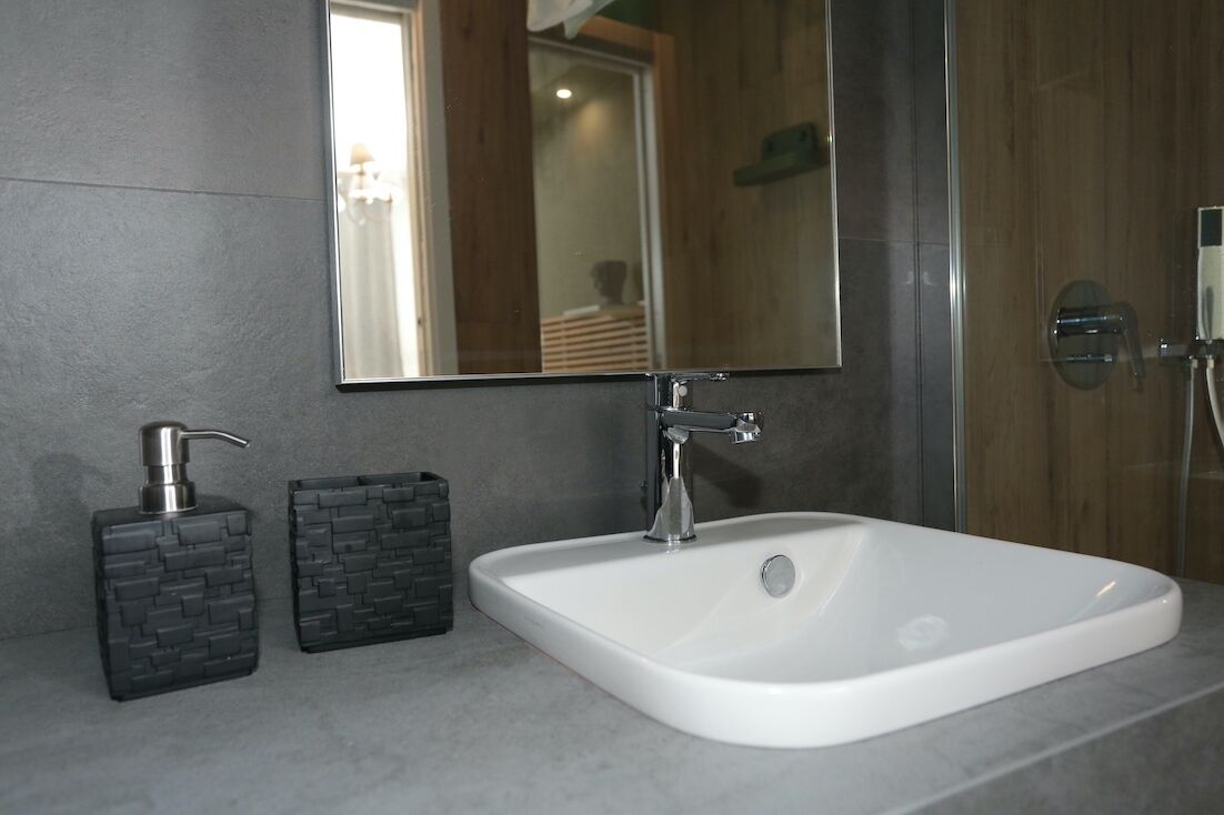 A bathroom with a white sink, a mirror, and two soap dispensers.