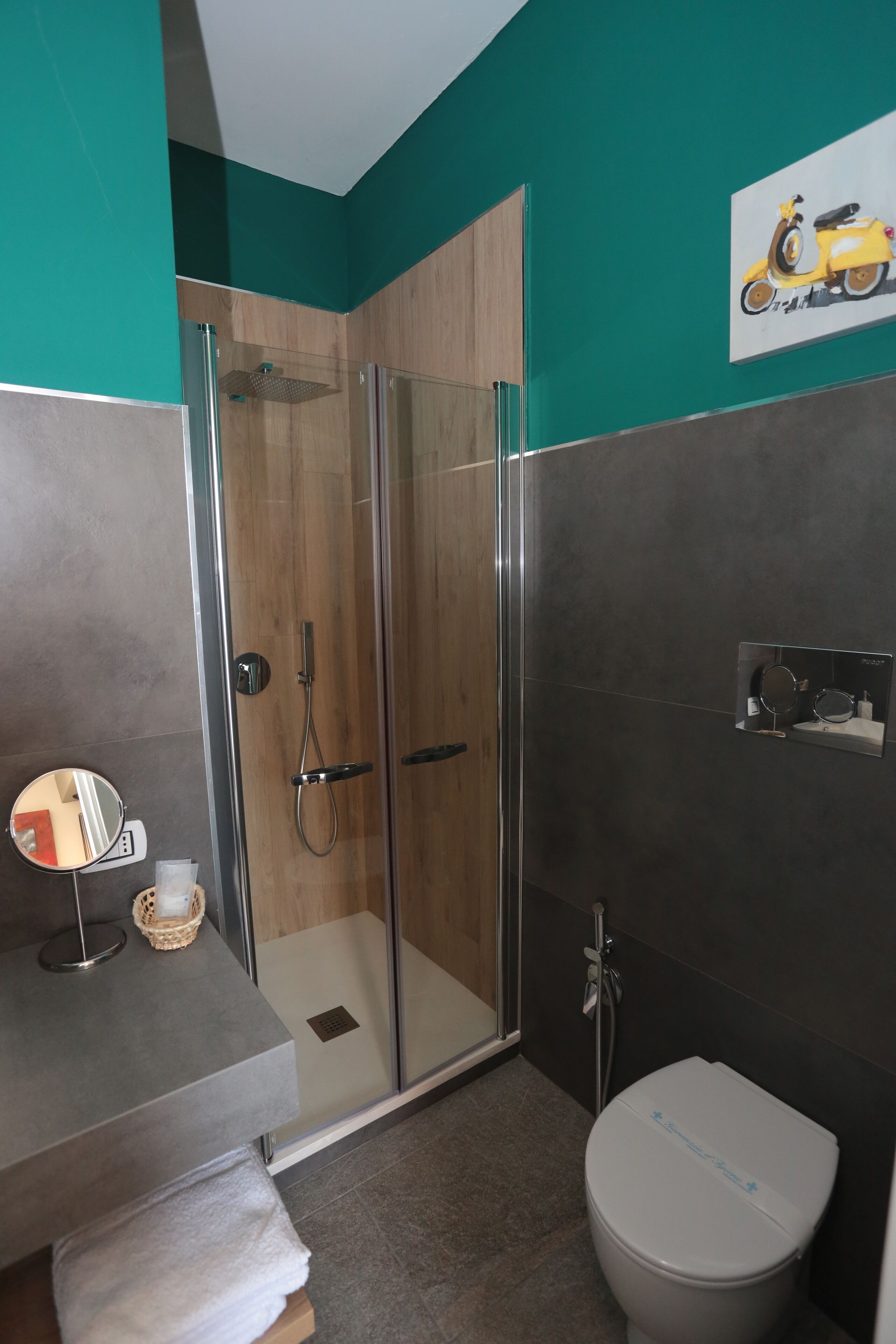 Un baño con ducha envuelta en vidrio, inodoro, lavamanos con espejo y dispensador de jabón de pared.
