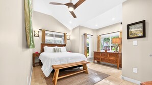 Une chambre à coucher avec un lit, un banc en bois, un ventilateur de plafond et une commode.