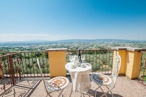 Un balcón con una mesa lista para dos personas, con vistas a un paisaje pintoresco.