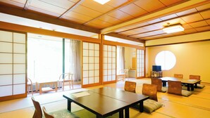 Une pièce de style japonais traditionnel, avec un sol recouvert de tatamis, des portes coulissantes et une petite table entourée de chaises.