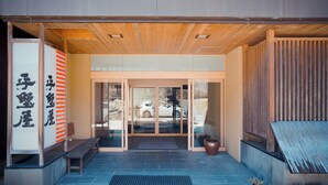 Une entrée moderne avec un plafond en bois, des portes en verre et un banc à l’extérieur.