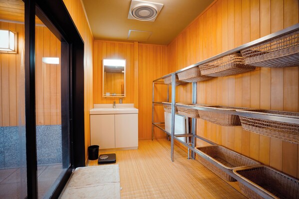 A bathroom with wooden walls, a sink, a mirror, and shelves with baskets. - HIRANOYA (Takayama)