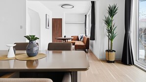 A modern living room with a dining table, sofa, and potted plants. - NORD BIRCH (Tobetsu)