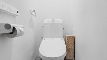 A modern bathroom with a toilet, toilet paper, and a wicker basket.