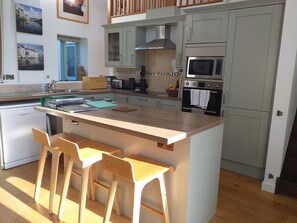 A modern kitchen with a central island, bar stools, stainless steel appliances, and a view of the city.