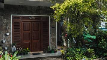 A stone building with a wooden door, potted plants, and a brick pathway.