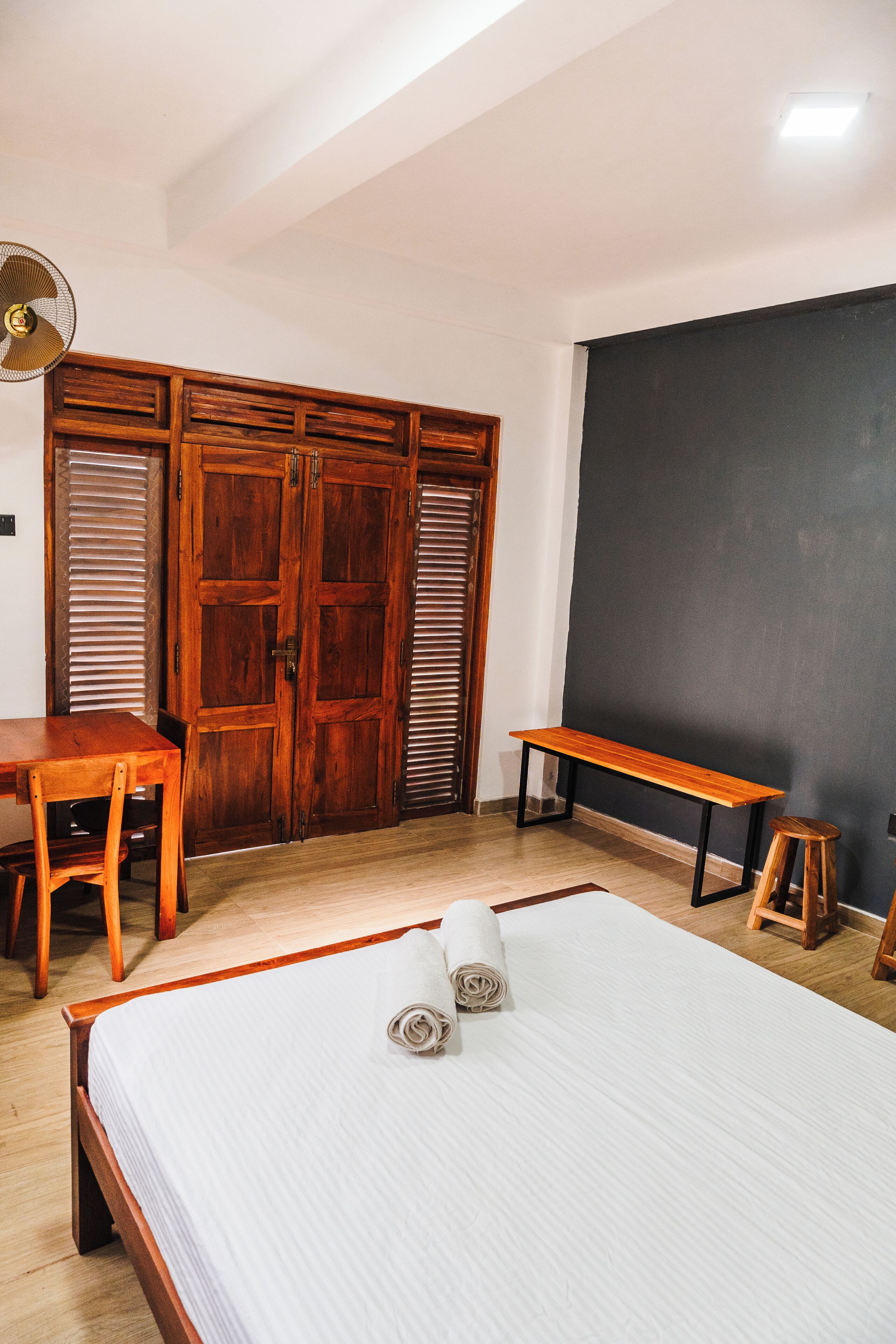 Ein Schlafzimmer mit einem hölzernen Bett, einem Schreibtisch aus Holz, einer Bank und einem Kleiderschrank.