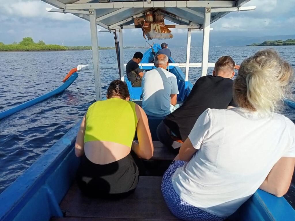 A boat with passengers, a covered area, and a body of water.