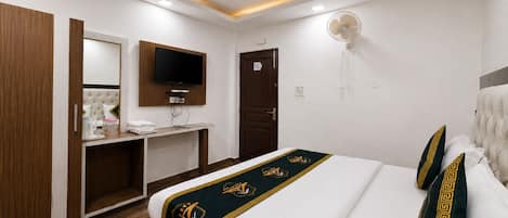 Habitación de hotel con cama, televisión montada en la pared, escritorio y armario.
