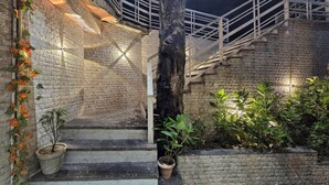 Uma escadaria com paredes de pedra, teto de madeira e plantas em vasos.