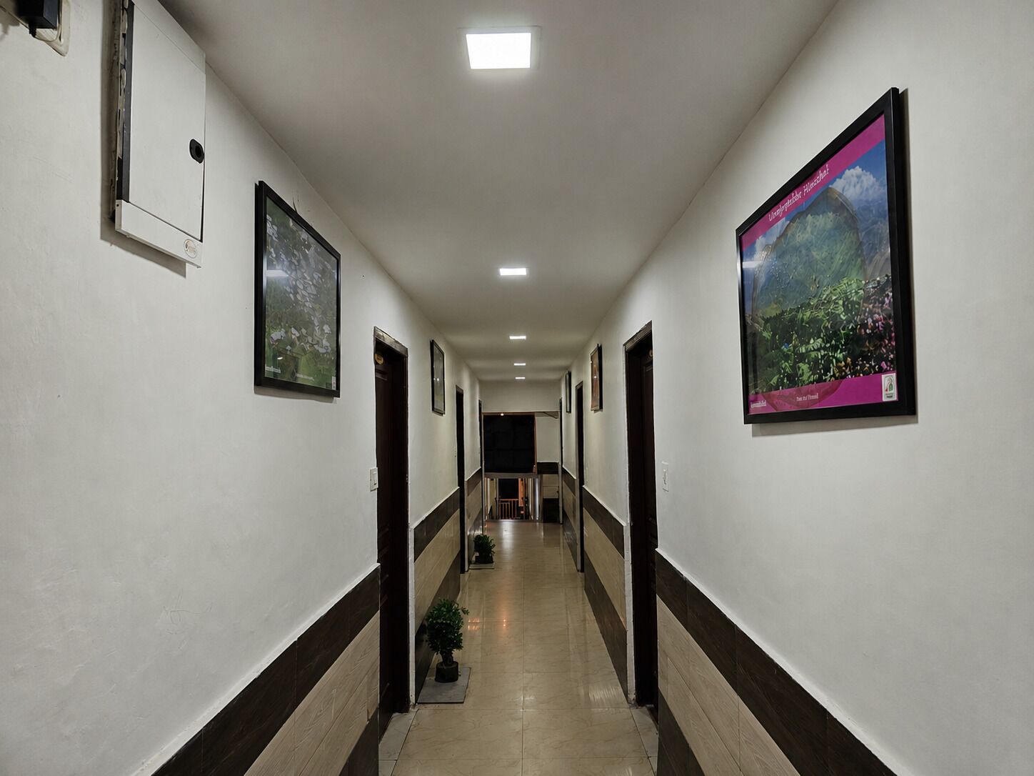 A hallway with framed pictures on the walls, a tiled floor, and a ceiling with recessed lighting.