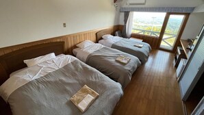 A room with four beds, wooden floors, a window with a view, and a ceiling fan. - Lodge Cowbell (Takko)