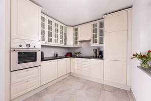 A kitchen with white cabinetry, a stove, and a coffee maker. - 5* Vacation Rental with a Terrace for 2 People (Schönau am Königssee)