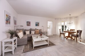 A modern living room with a sofa, coffee table, and dining area. - 5* Vacation Rental with a Terrace for 2 People (Schönau am Königssee)