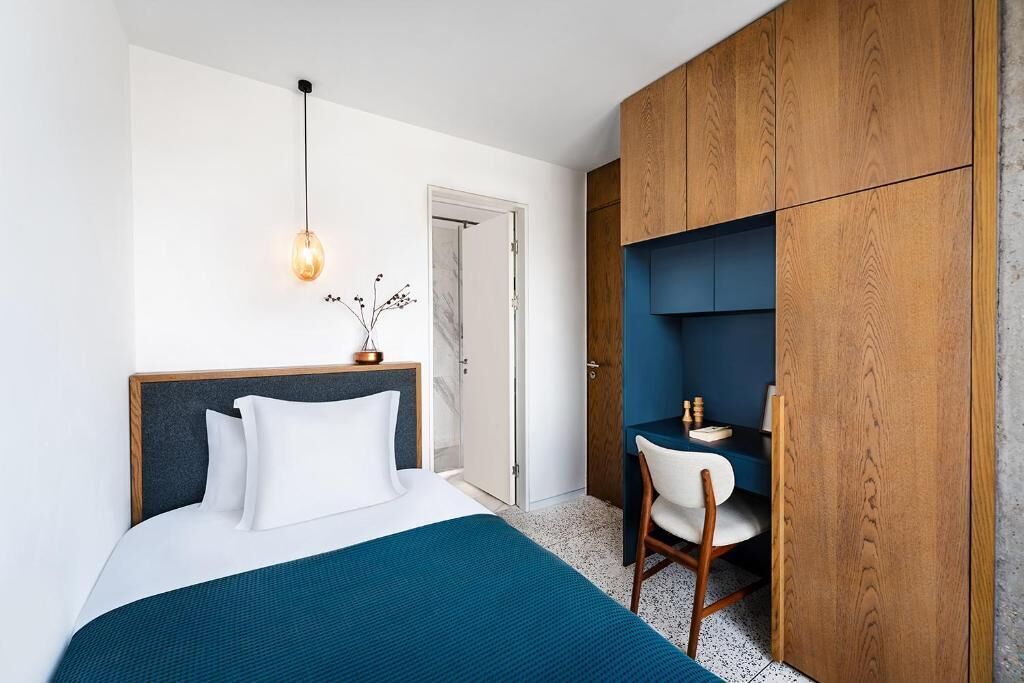 A bedroom with a bed, a desk, and a wardrobe.