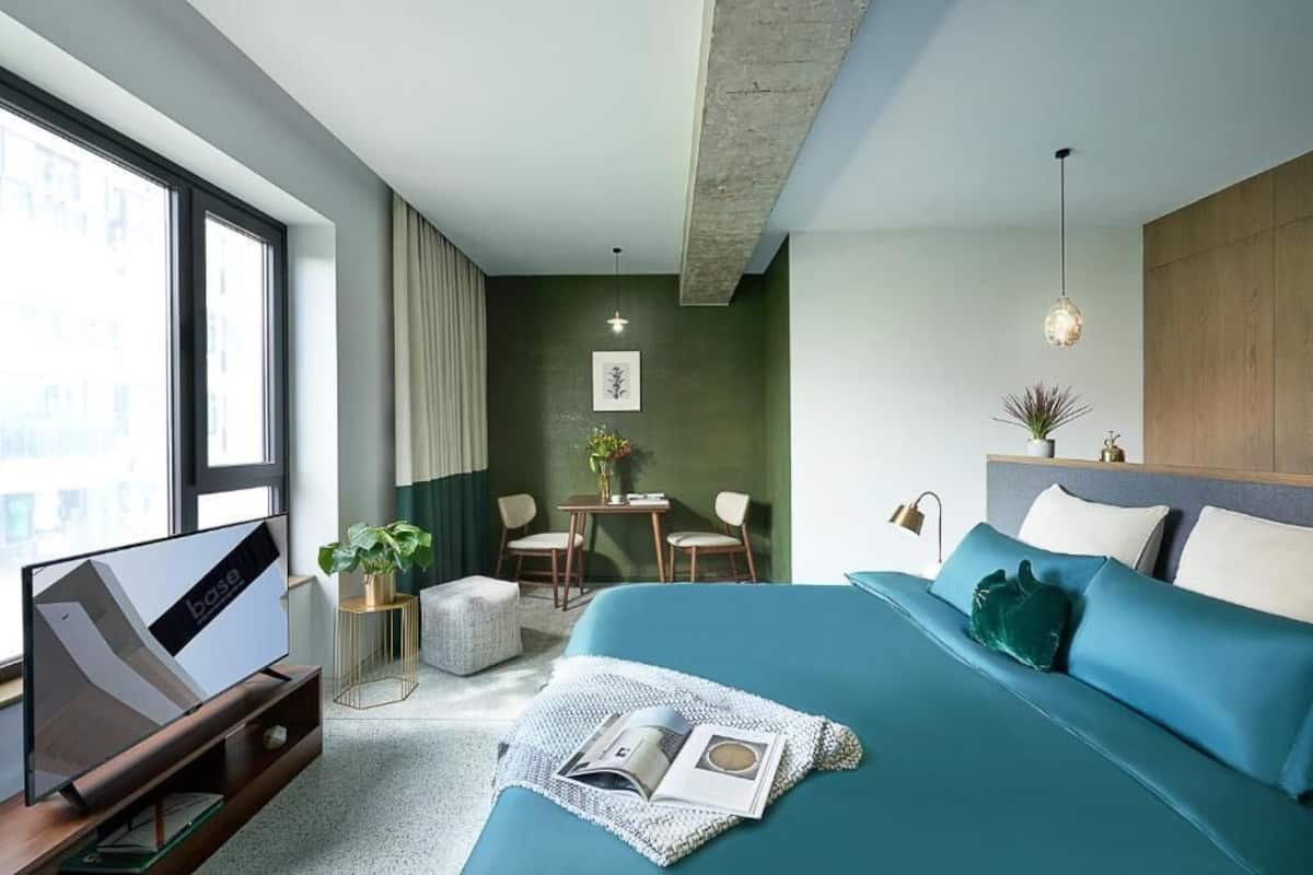 Una habitación de hotel moderna con una cama grande, televisión, zona de comedor y vista a la ciudad.