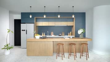 A modern kitchen with a central island, bar stools, pendant lighting, and a backsplash.