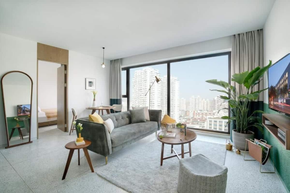 Una sala de estar moderna con un sofá, una mesa de centro y un ventanal con vistas a la ciudad.