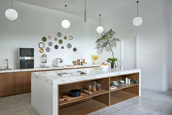 A modern kitchen with a central island, pendant lights, and a variety of decorative plates on the wall. - basePLUS-Binjiang Serviced Apartment (Shanghai)