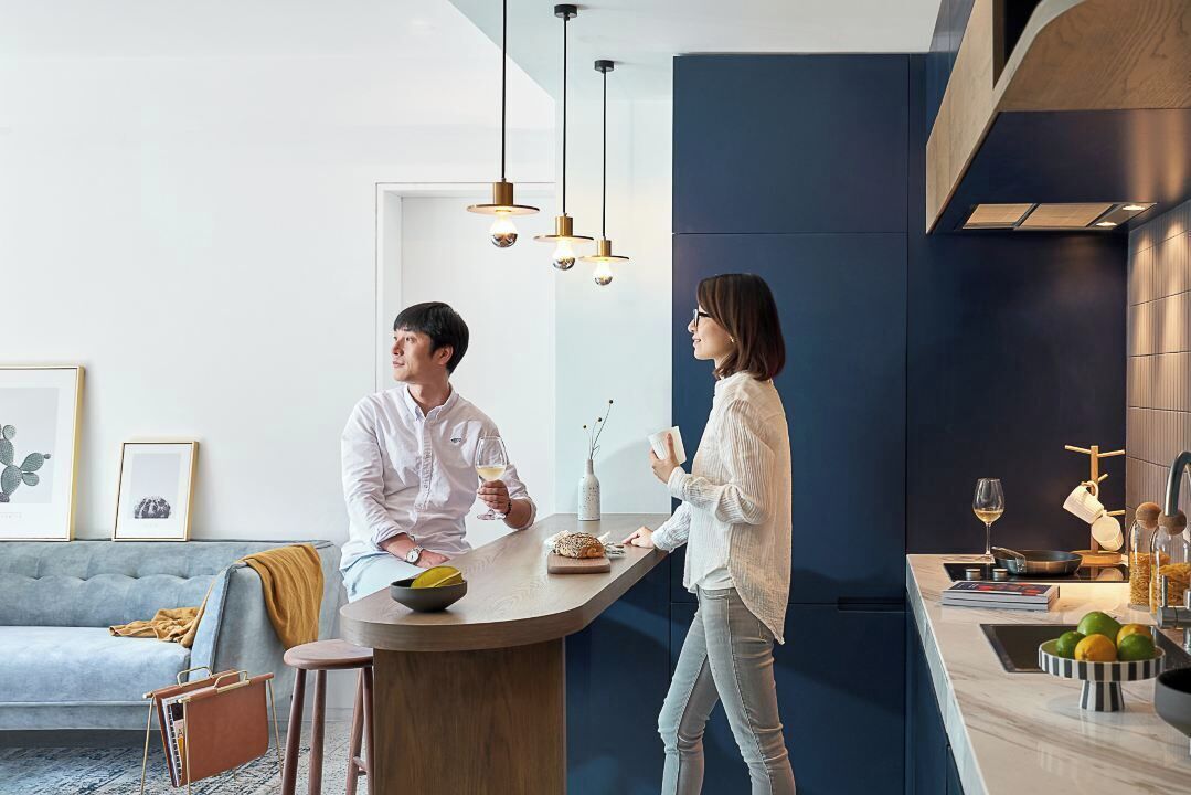 A modern kitchen with a bar area, a sofa, and framed artwork on the wall.