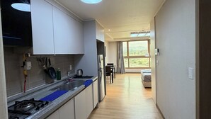 Una cuina moderna amb fogó a gas, armaris i finestra.