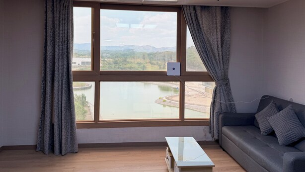 Una habitació amb una finestra gran, un sofà i una taula petita.