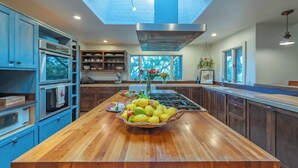 Una cucina con isola in legno, elettrodomestici integrati e un lucernario.