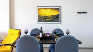 En matplats med ett bord dukat för fyra personer, en gul stol och en inramad landskapsmålning på väggen.