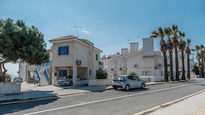 A residential street with two-story houses, a clear sky, and a palm tree. - Beach Escape Apartment (Pyla)