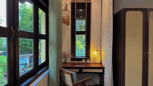 Una habitación con escritorio, silla, ventana con persianas y un mueble con diseño perforado.