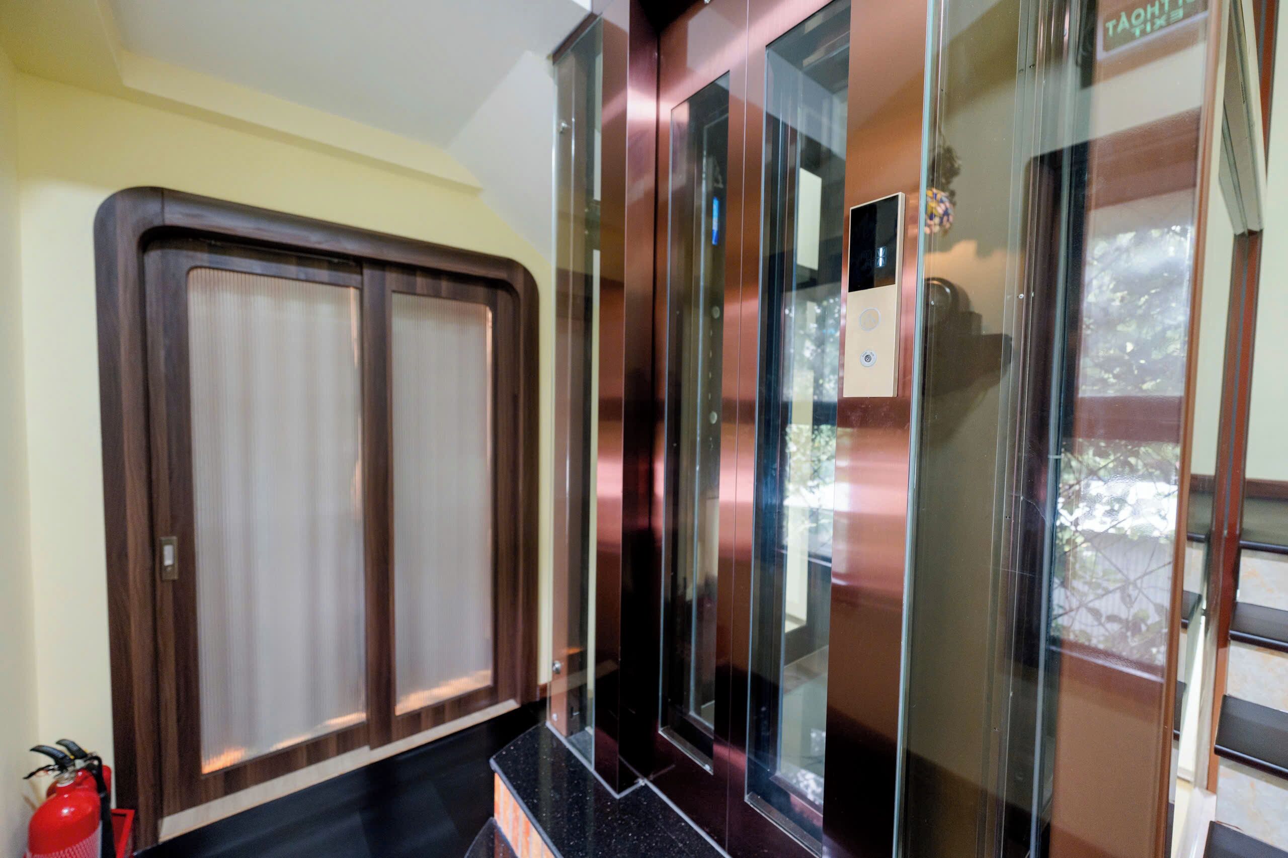 An elevator with glass panels and a fire extinguisher on the wall.
