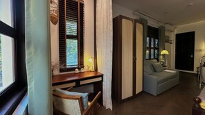 Una habitación con escritorio, silla, sofá y un ventanal con persianas.