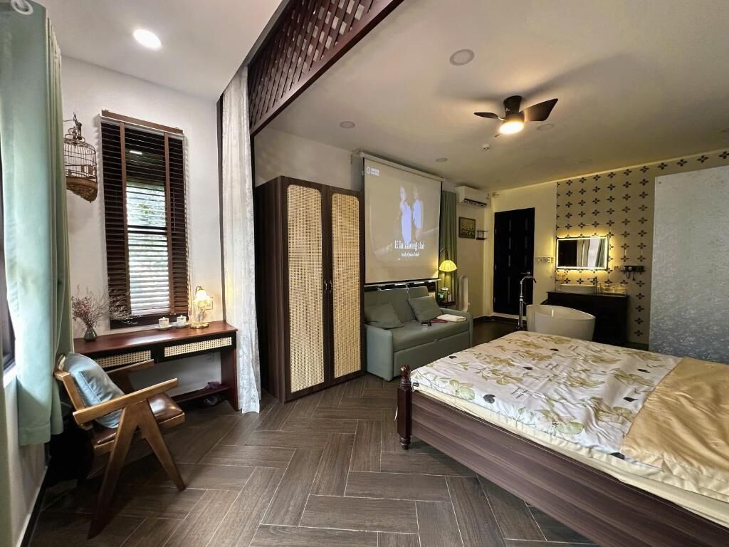 A bedroom with a bed, a desk, a chair, a wardrobe, and a ceiling fan.