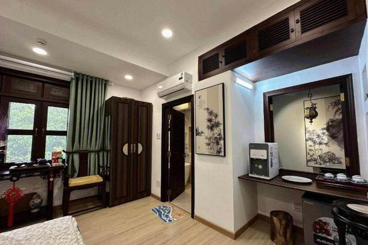 A hotel room with a bed, a desk, a chair, a mirror, a sink, and a toilet.
