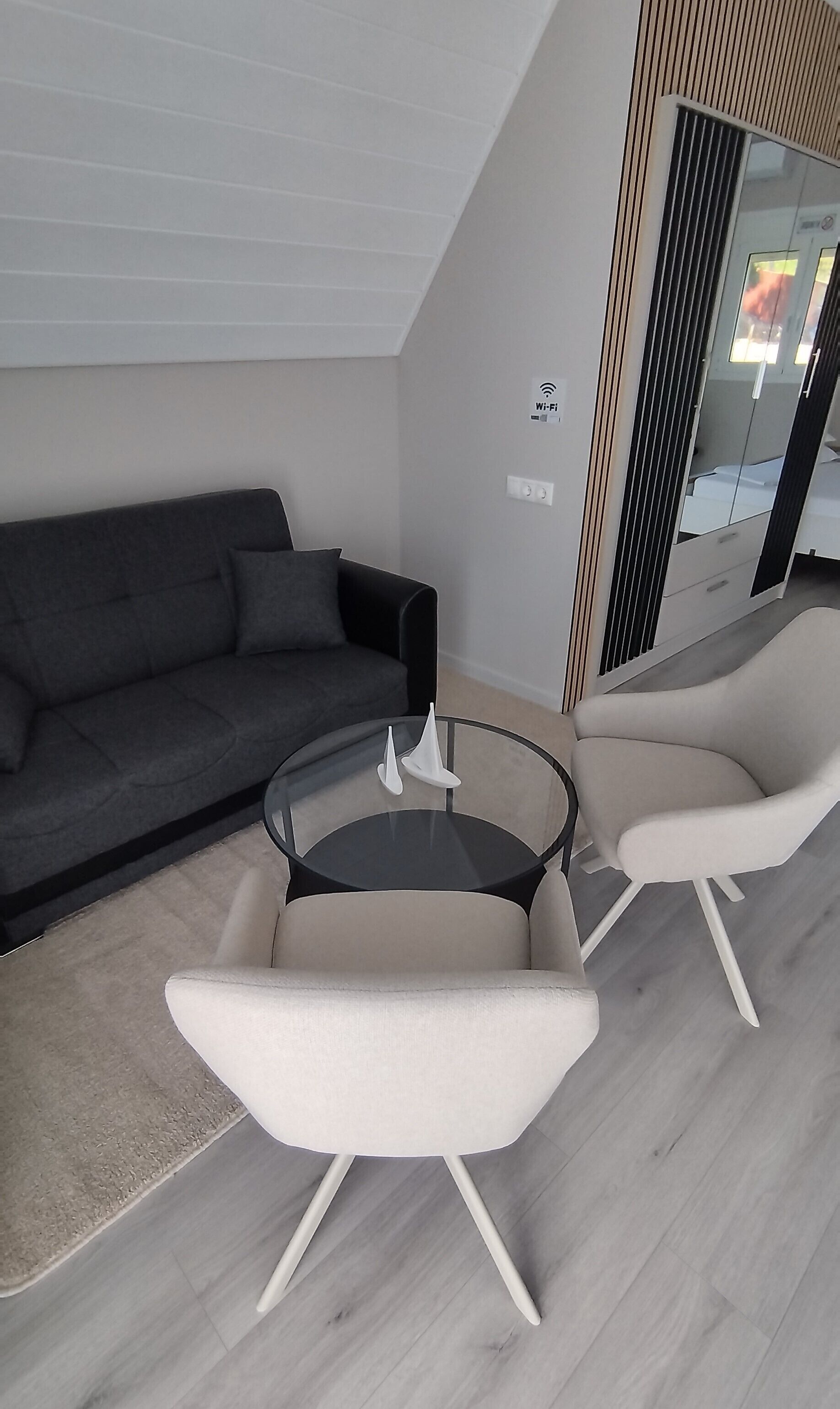 Ein modernes Wohnzimmer mit einer Couch, zwei Sesseln und einem Glastisch.