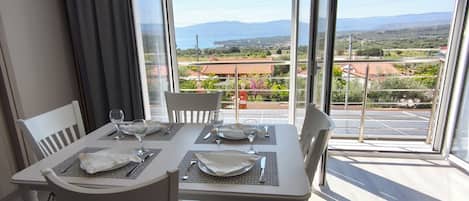 A dining area with a table set for four, large windows with a view of the landscape, and a ceiling with a striped pattern.