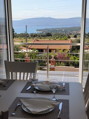 A dining table with a view of a vineyard and mountains. - ☀️ SUNNY HOME: Panoramic Loft with Gulf & Mountain Views with private parking (Loutraki)