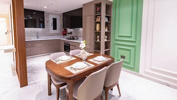 A dining area with a marble floor, a wooden table set for four, and a green door in the background.