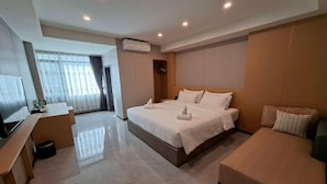 Una habitación de hotel moderna con una cama grande, un sofá, un televisor y un escritorio.