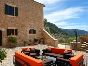 A stone building with outdoor seating and a view of a mountainous landscape. - Biniforani Nou 12 pax (Bunyola)