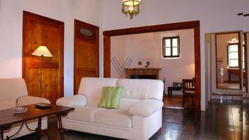 A living room with a white sofa, a wooden floor, a lamp, and a fireplace.