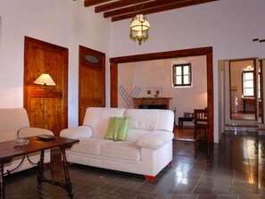 A living room with a white sofa, a wooden floor, a lamp, and a fireplace. - Biniforani Nou 12 pax (Bunyola)